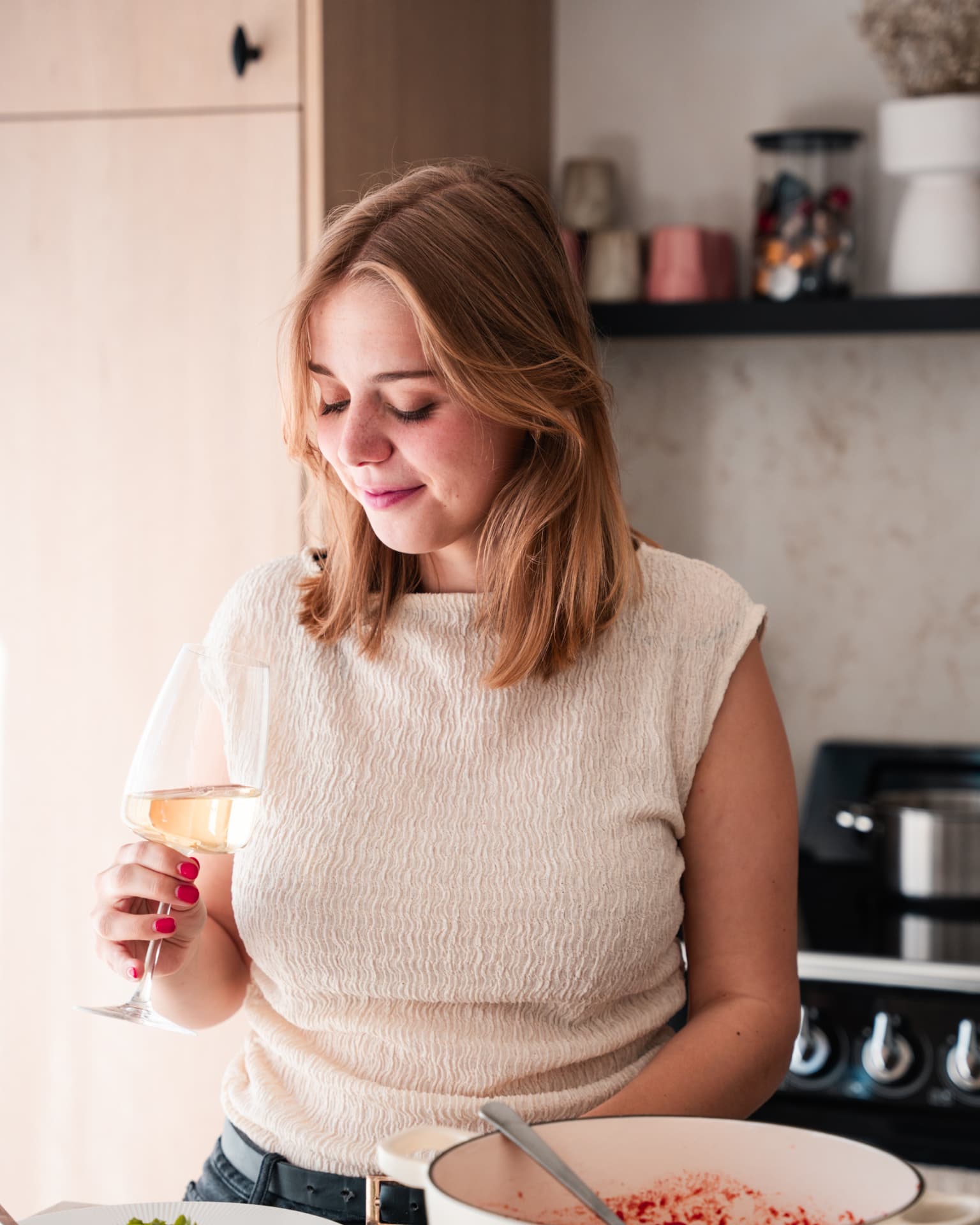 Vrouw die glimlacht met een glas wijn in warm licht