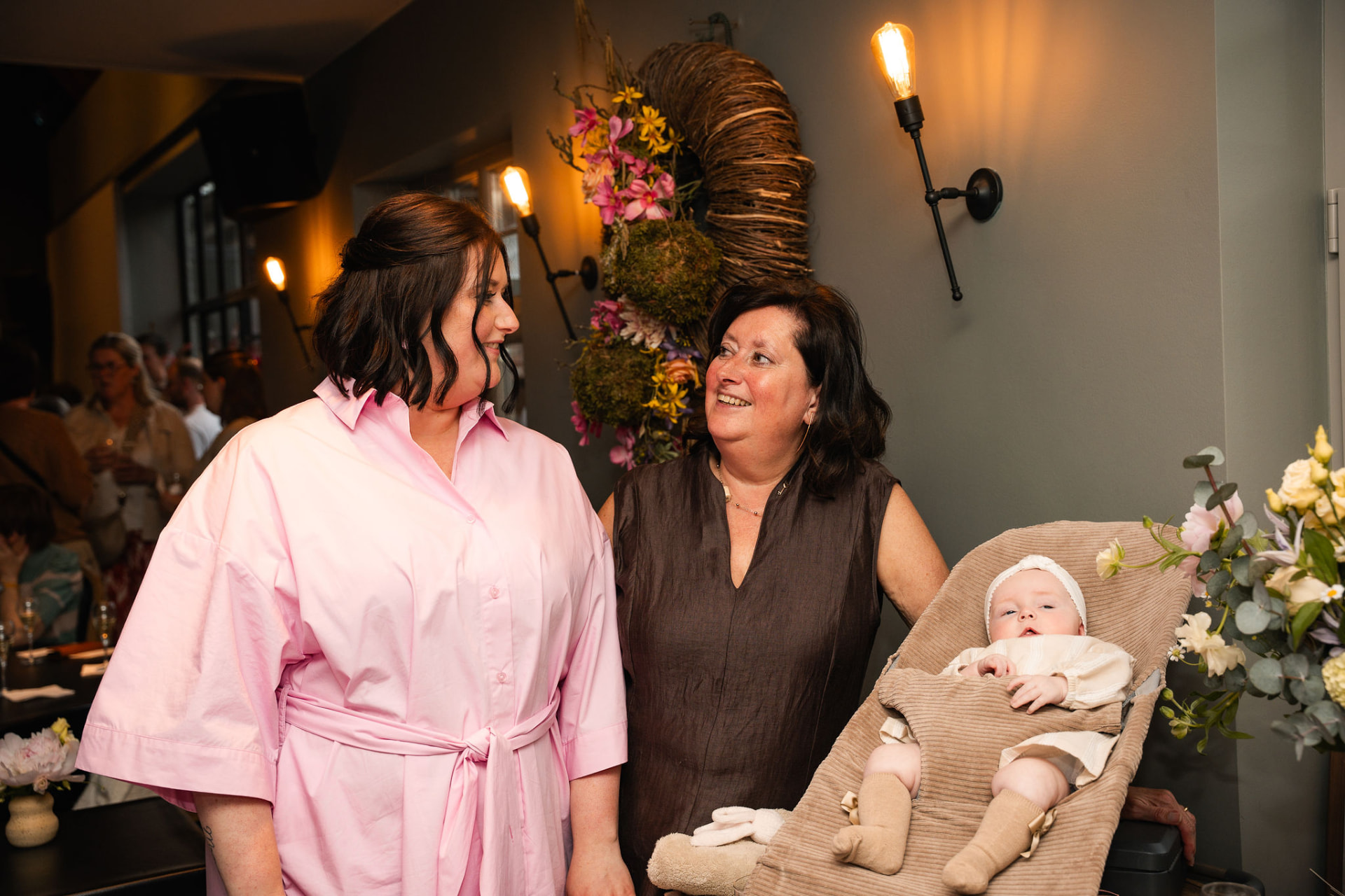 Mama en oma lachen naar elkaar naast Manon in haar wipstoeltje