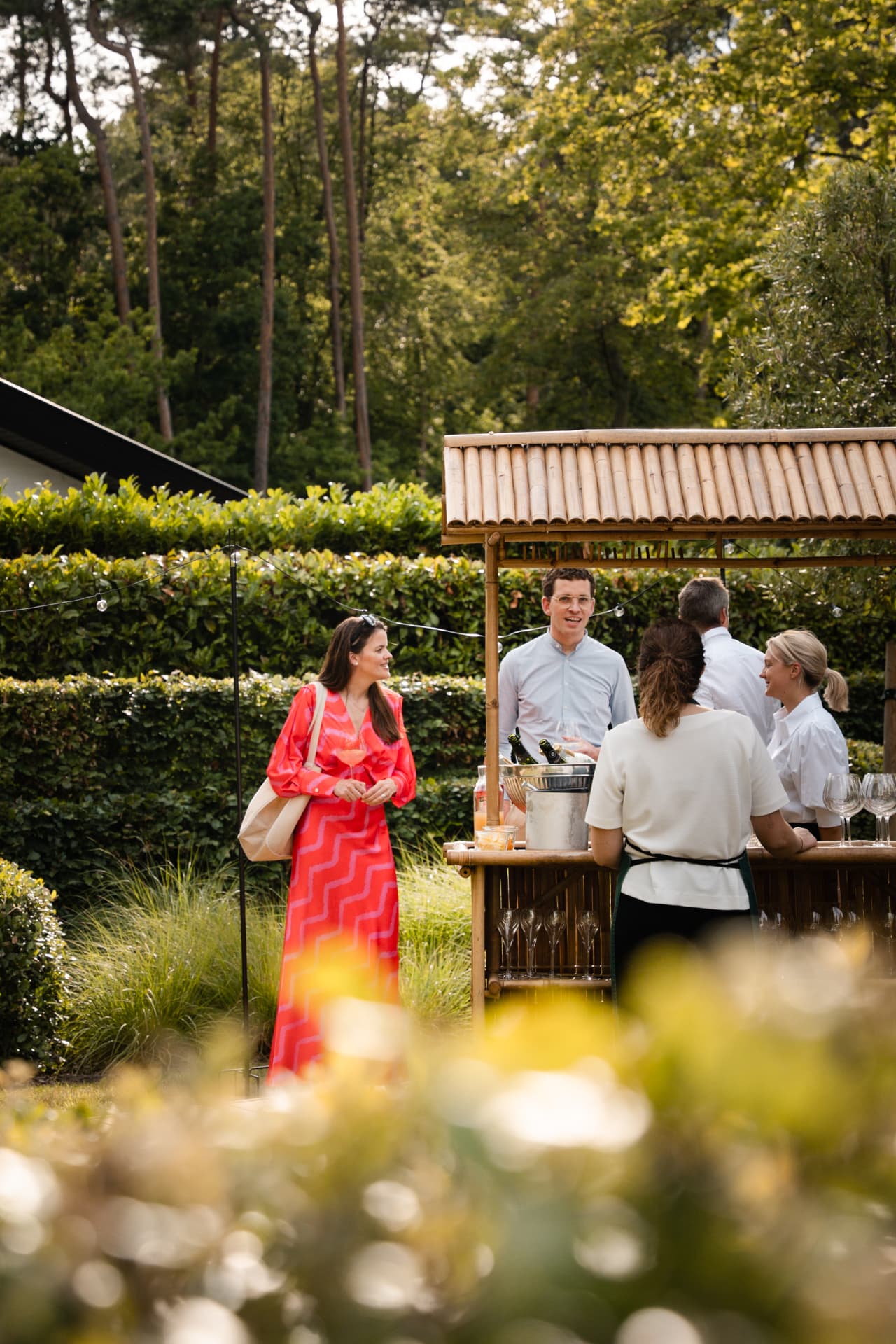Gasten aan de bamboebar met champagne in de tuin