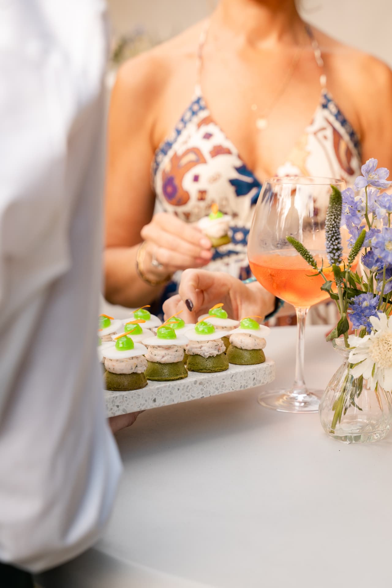Hapjes op een terrazzoplateau met een spritz en bloemen