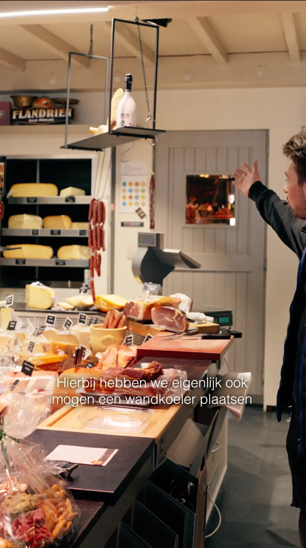 Wandkoeler in een slagerij met toonbank vol kaas en charcuterie