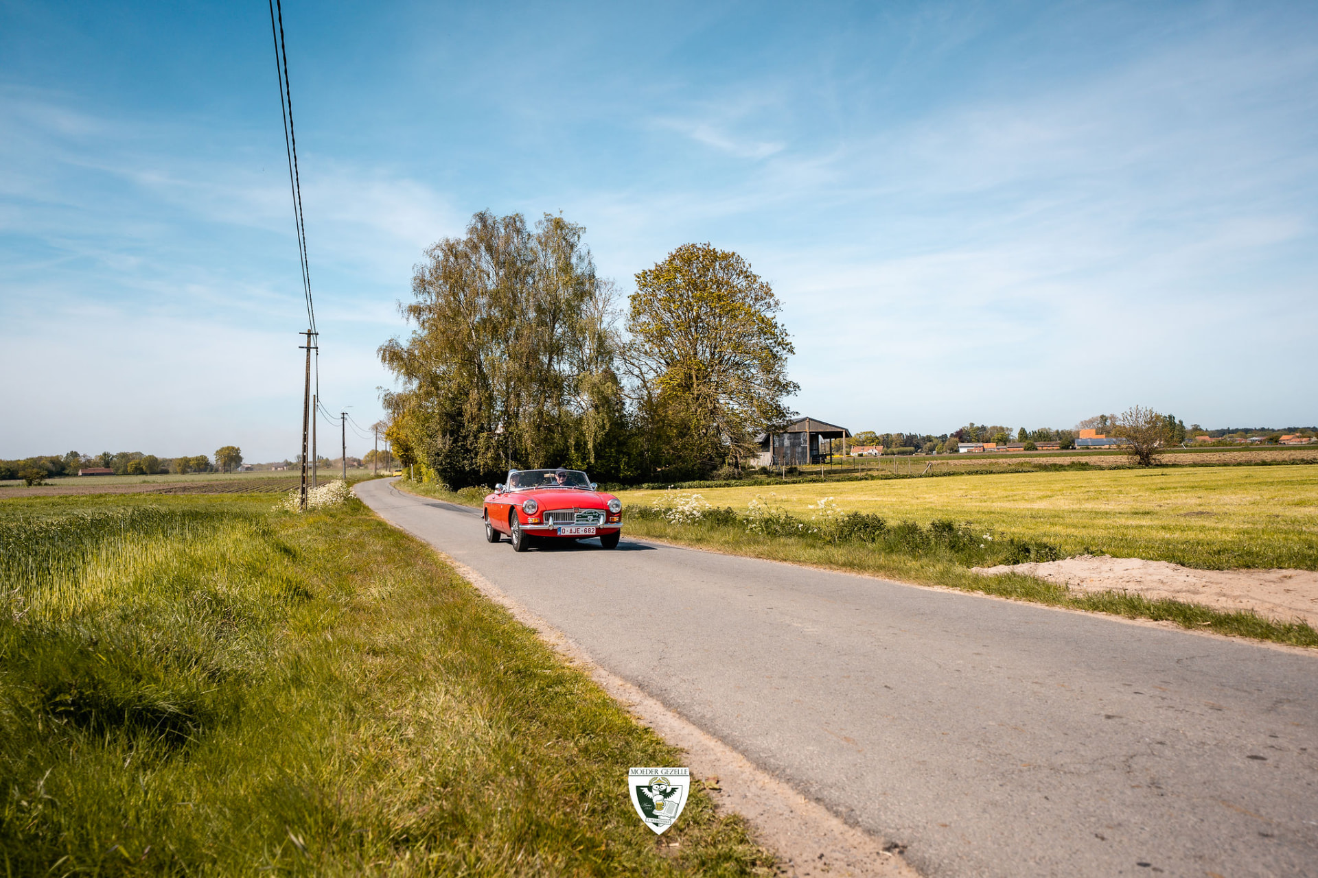 Rode MB cabriolet op een landweg tussen de velden