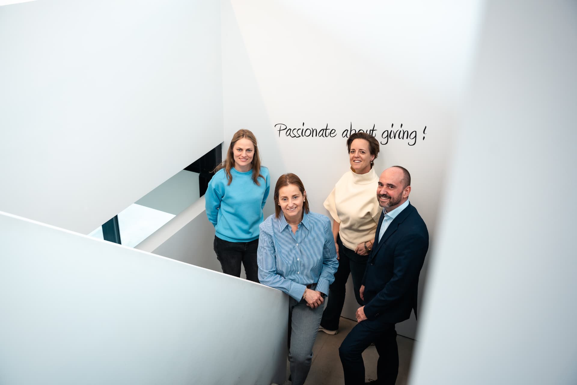 Het team van Attent op de trap bij de slogan Passionate about giving
