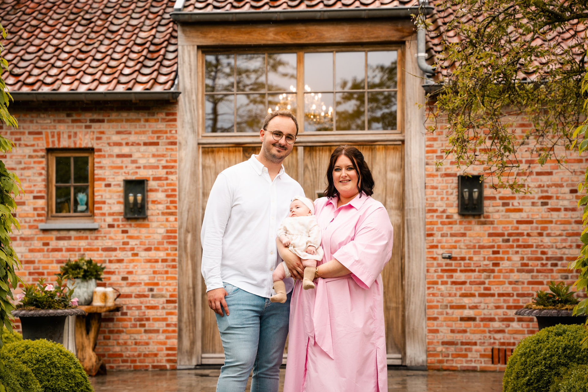 Ouders met Manon voor de bakstenen gevel van de feestzaal