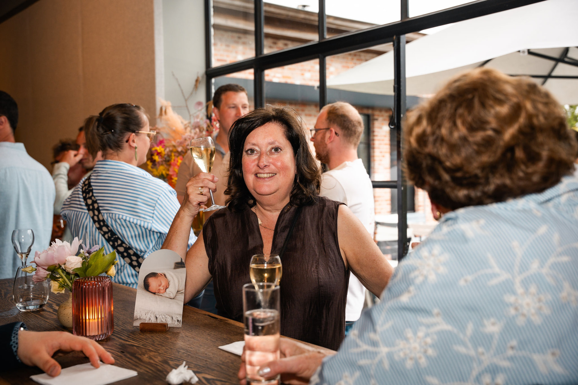 Gast heft haar glas cava aan tafel tijdens de babyborrel