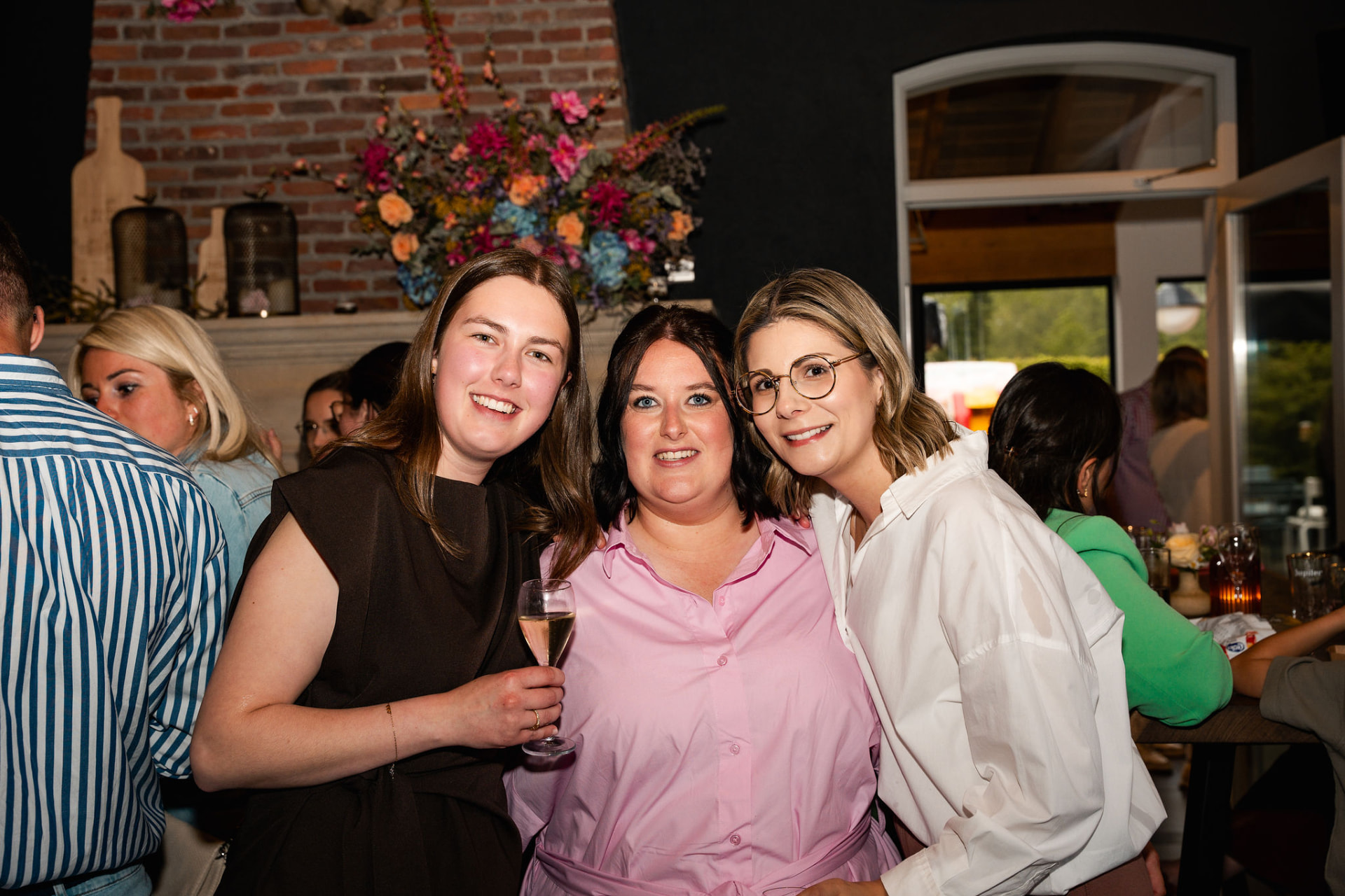 Drie vriendinnen lachend samen op de foto met een glas cava