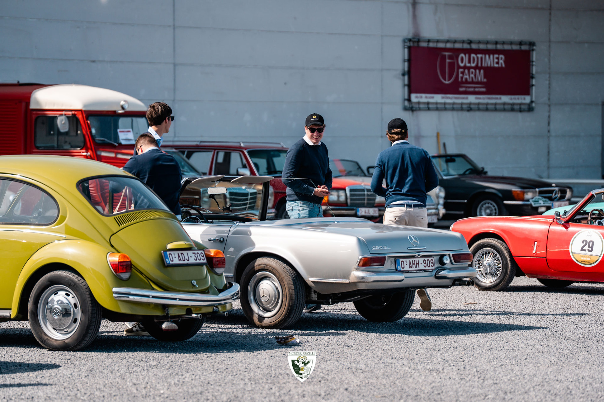 Deelnemers in gesprek bij een zilveren Mercedes 250 SL en een groene Kever