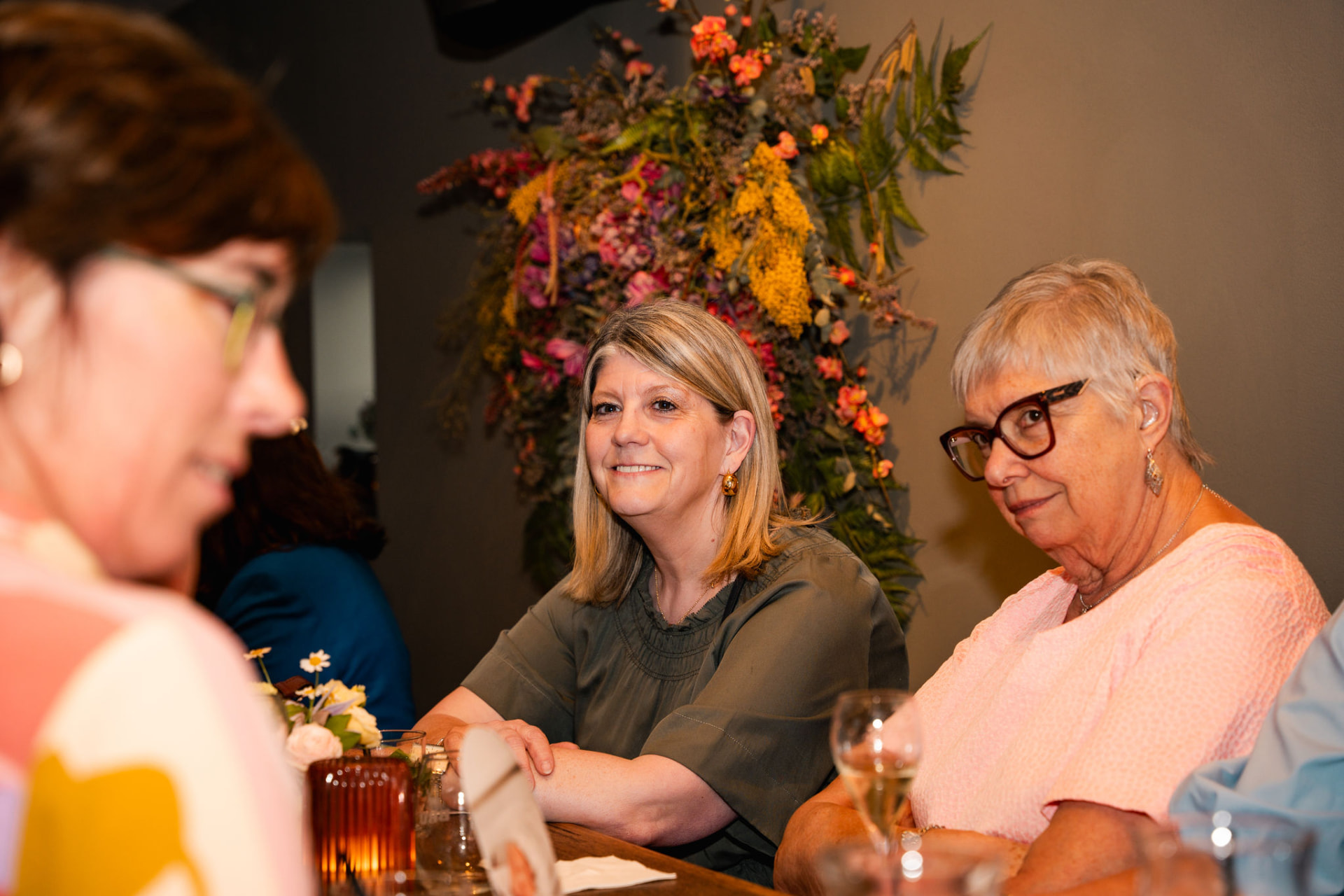 Gasten lachend aan tafel voor een groot droogbloemstuk