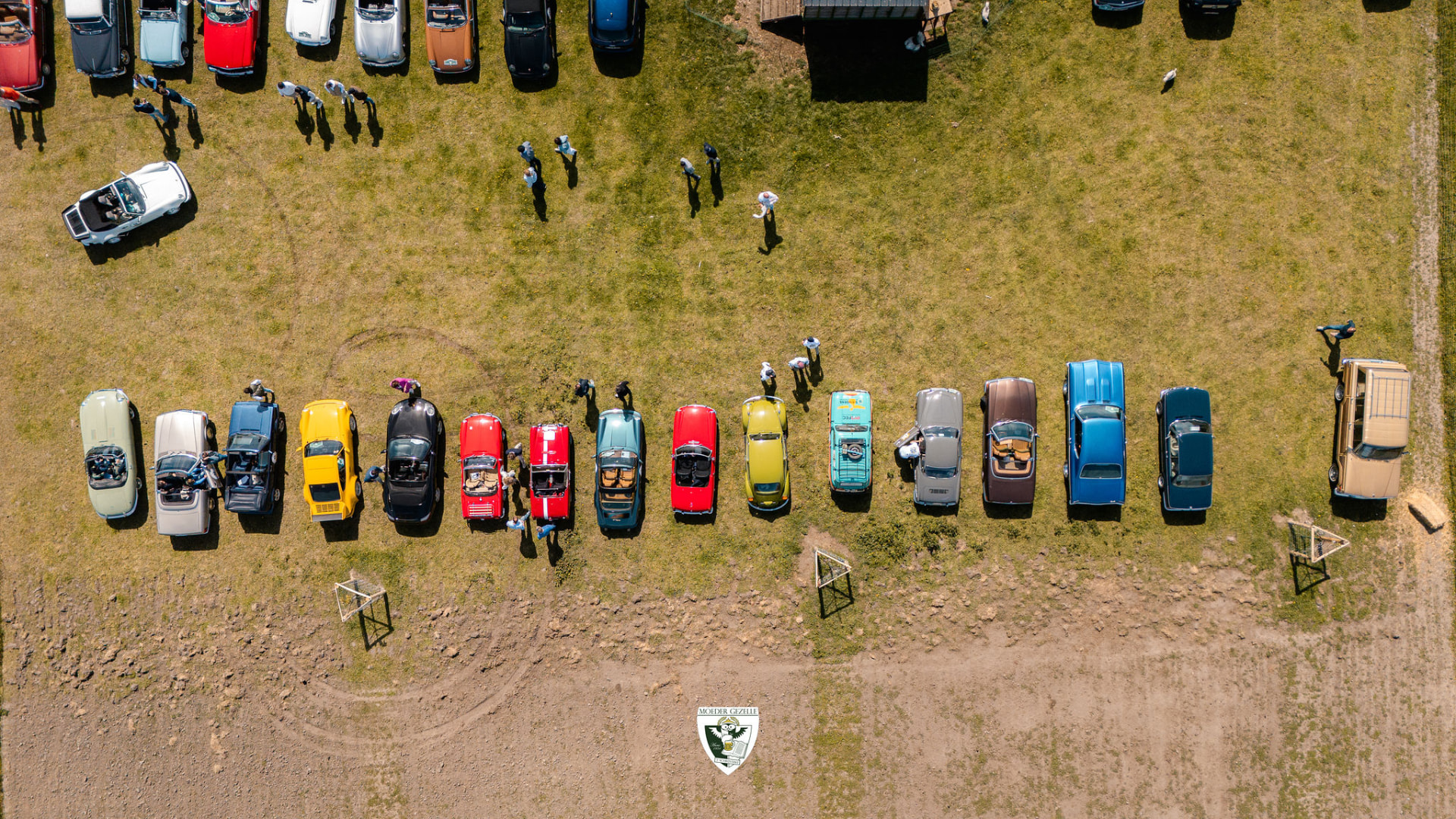 Luchtbeeld van een rij oldtimers op een grasveld