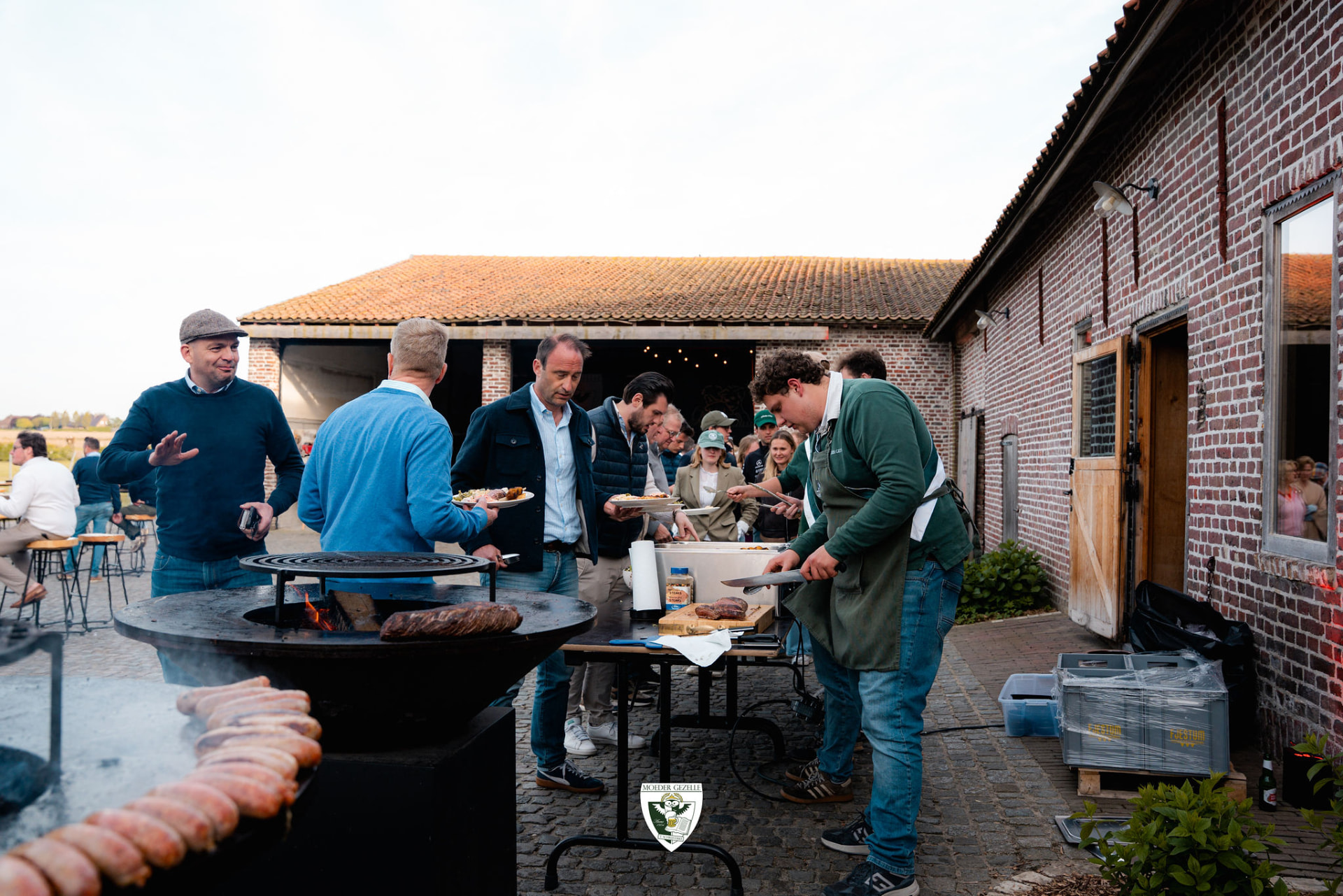 Gasten schuiven aan bij de barbecue naast de bakstenen schuur