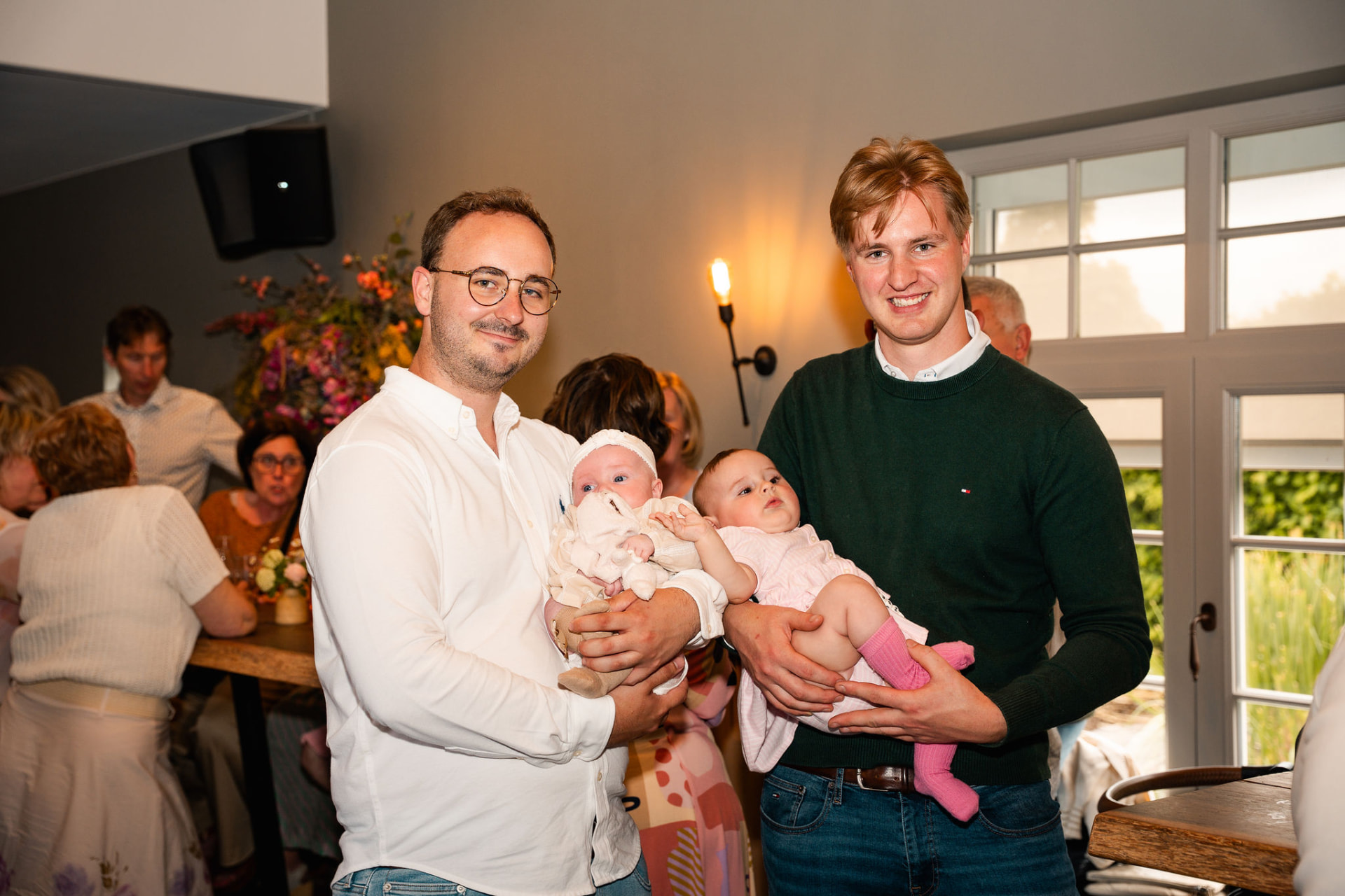 Papa en een gast houden elk een baby in de armen