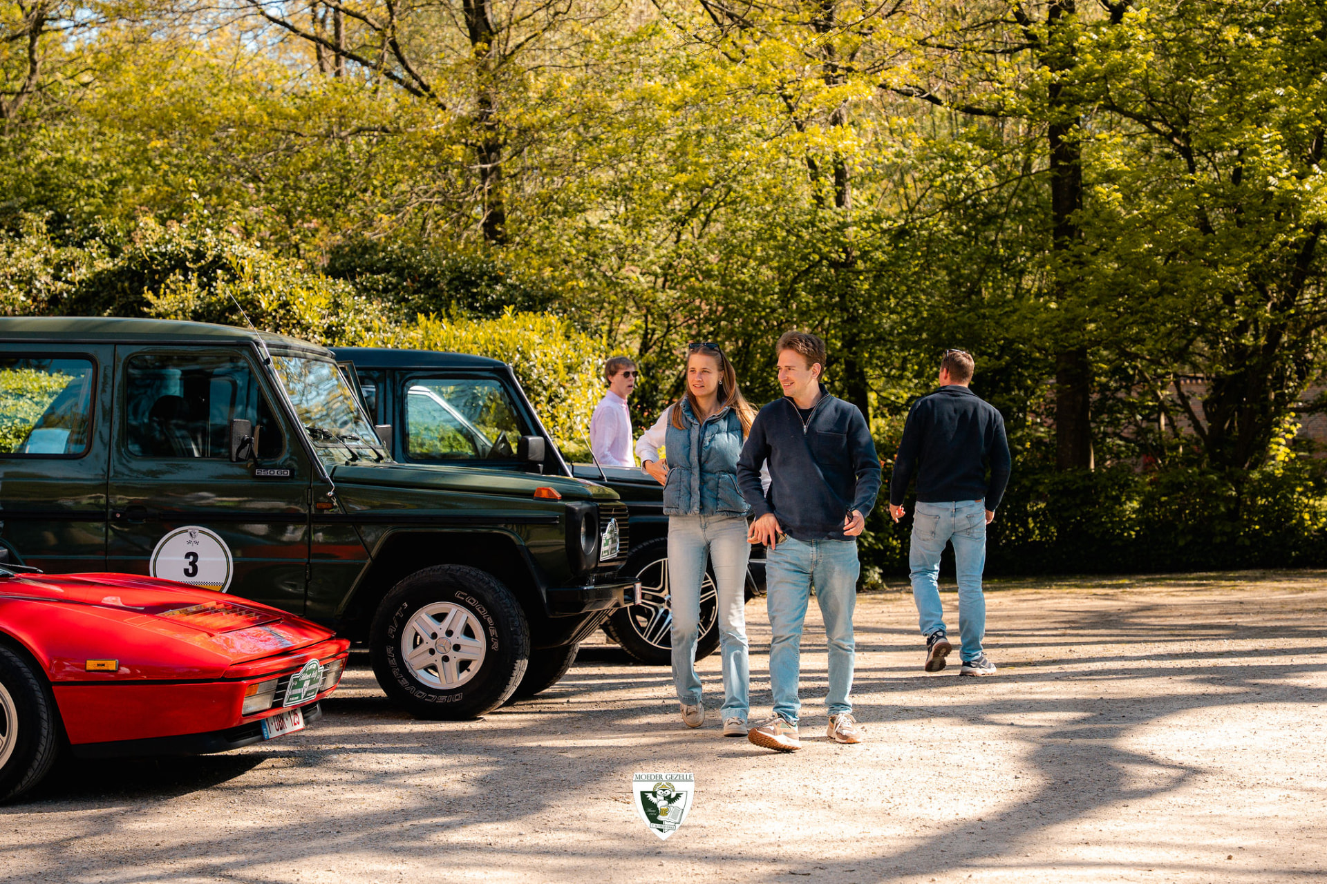 Deelnemers wandelen tussen geparkeerde klassiekers