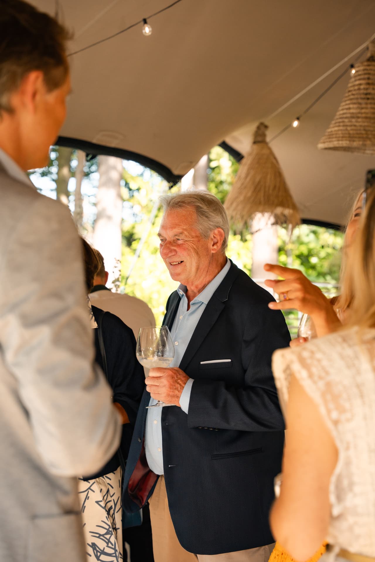Lachende gast met een glas wijn onder de tent