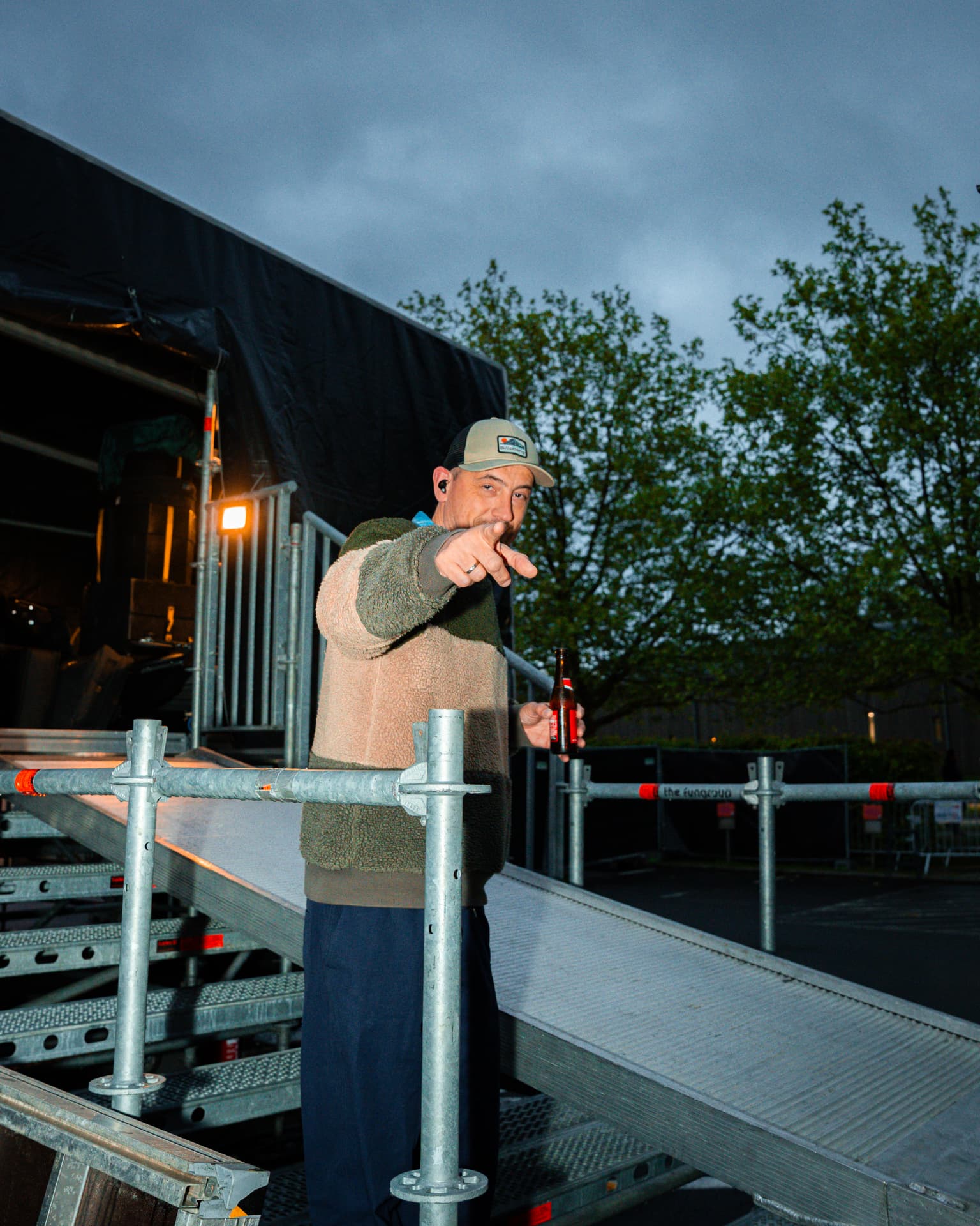 Crewlid met een biertje op de podiumtrap in de avondschemering