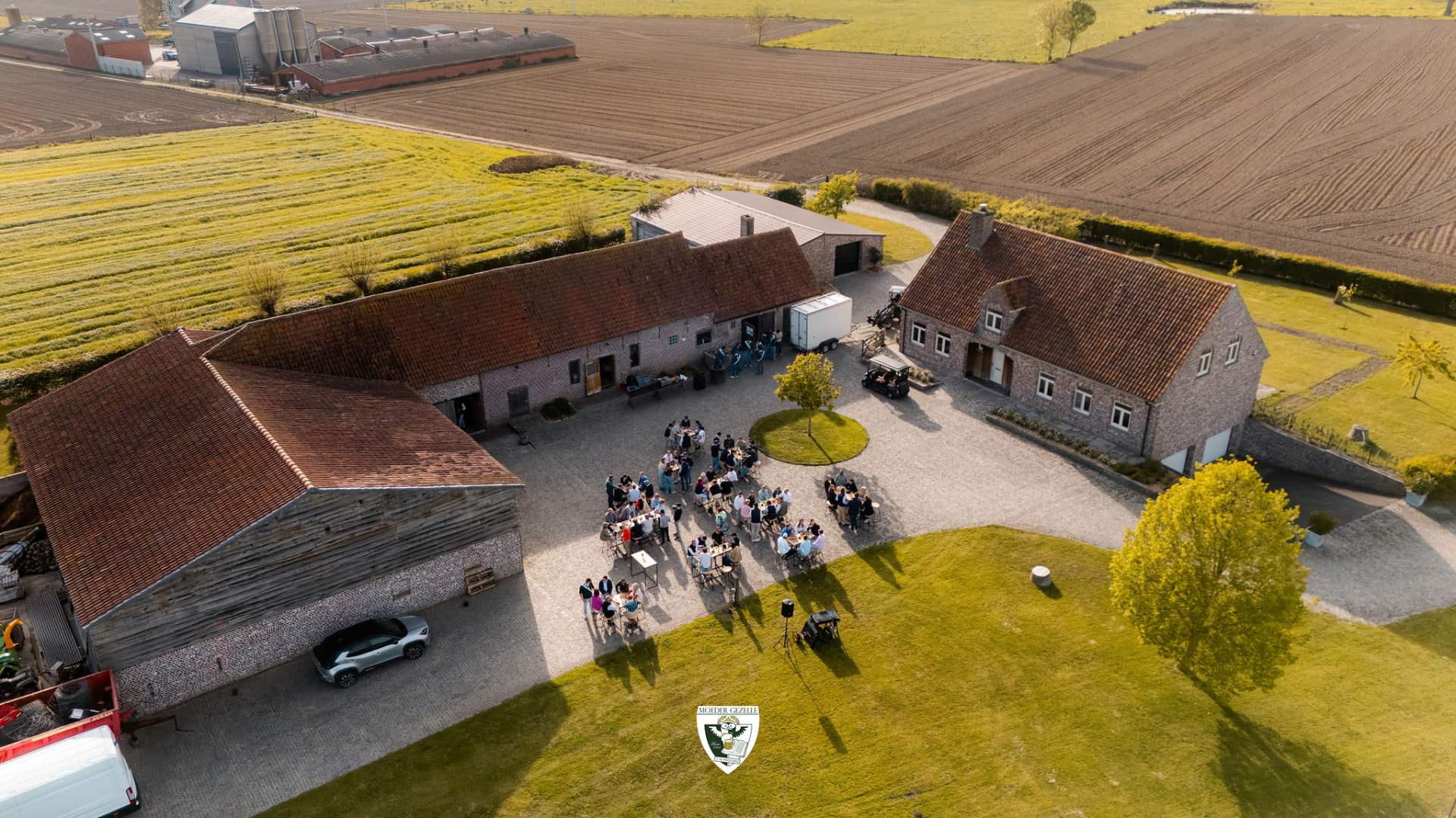 Luchtbeeld van de hoeve met gasten aan tafels op het binnenplein