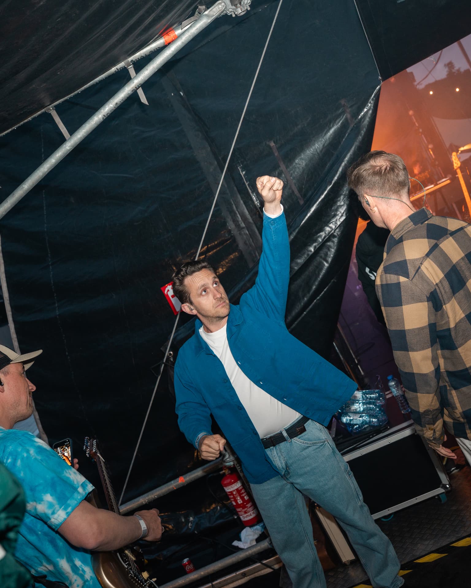 Bandlid met opgeheven vuist backstage naast het podium