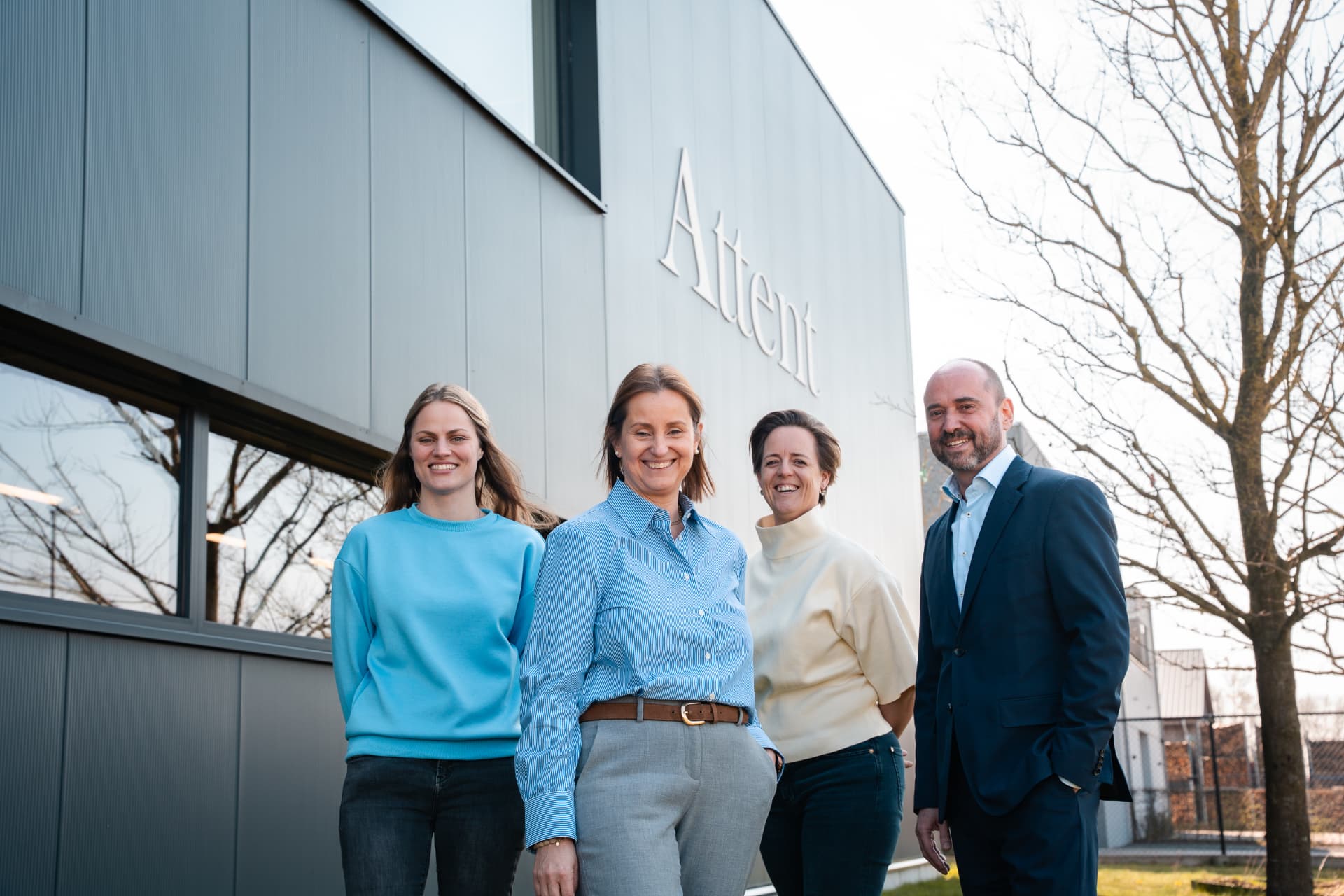 Het team van Attent lachend buiten aan de gevel