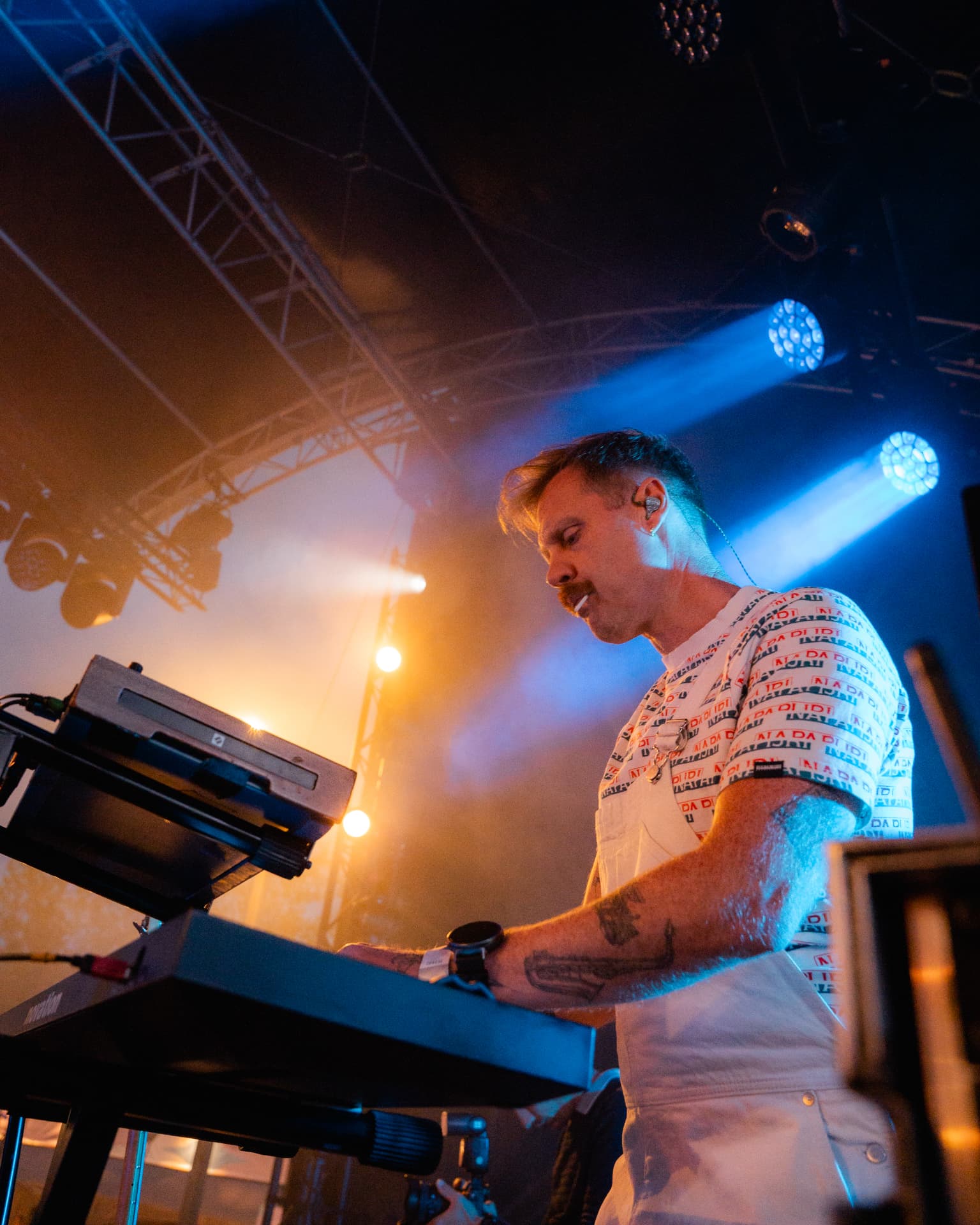 Toetsenist in blauw en oranje licht achter zijn keyboard