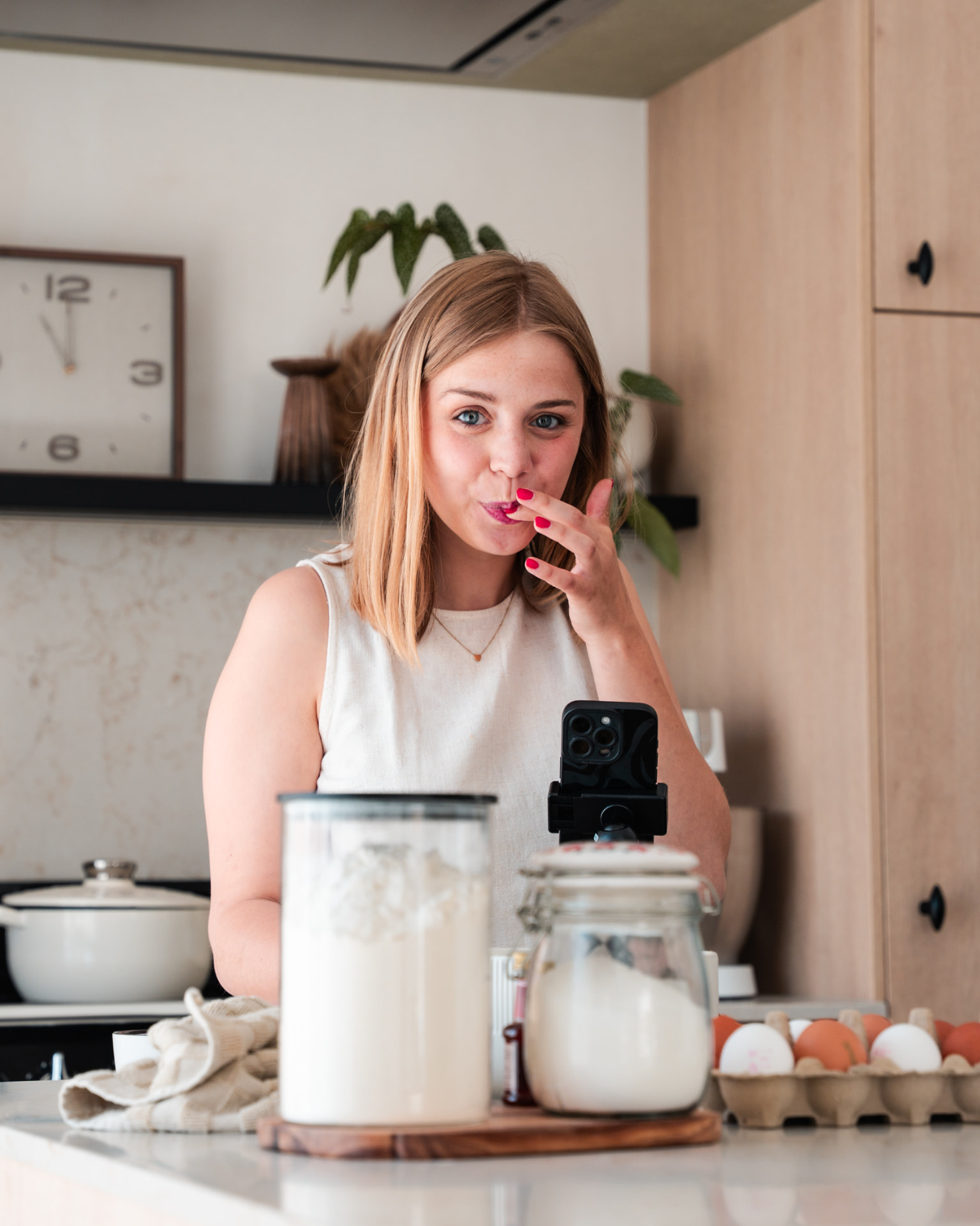 Vrouw die haar vinger aflikt achter een telefoon op statief