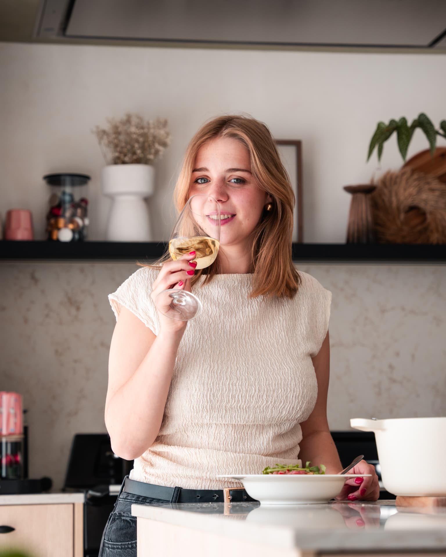 Vrouw met een glas witte wijn in de keuken