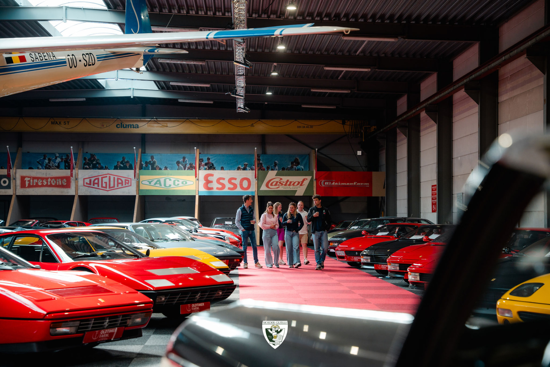 Bezoekers wandelen tussen rode Ferrari's in de hal van Oldtimer Farm