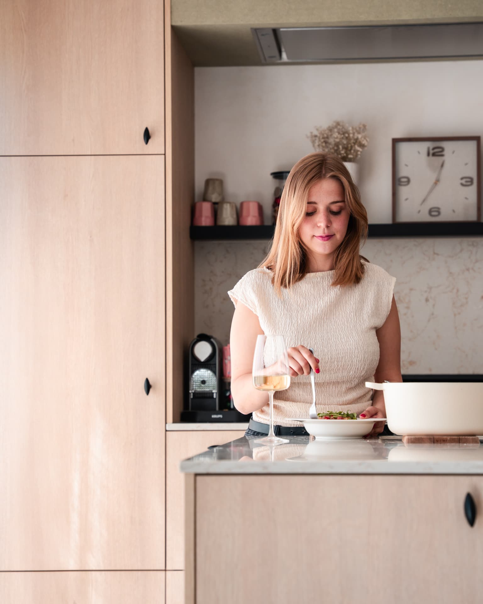 Vrouw die een bord pasta opmaakt aan het keukeneiland