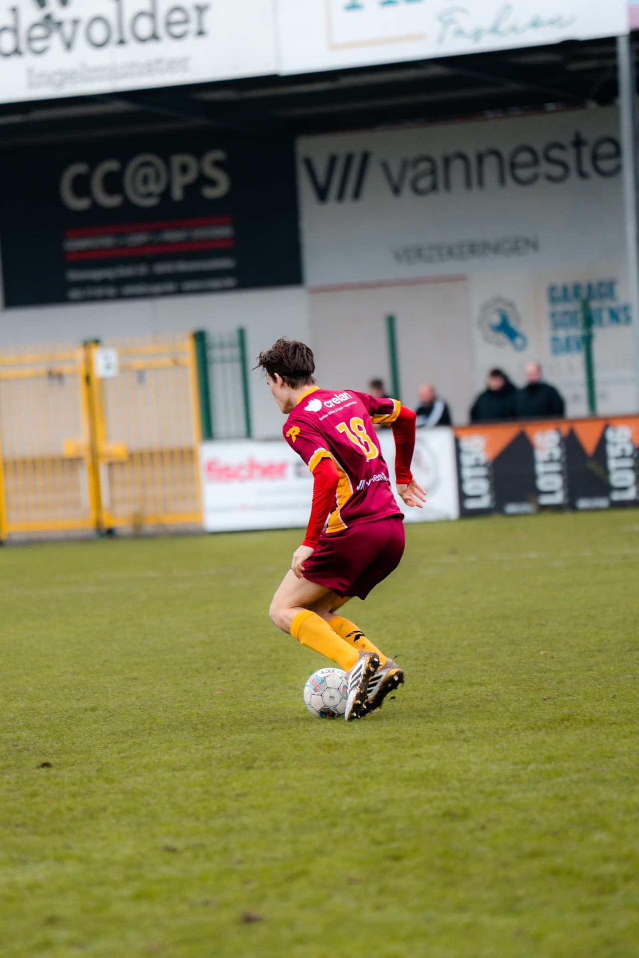 Speler met rugnummer 18 draait weg met de bal