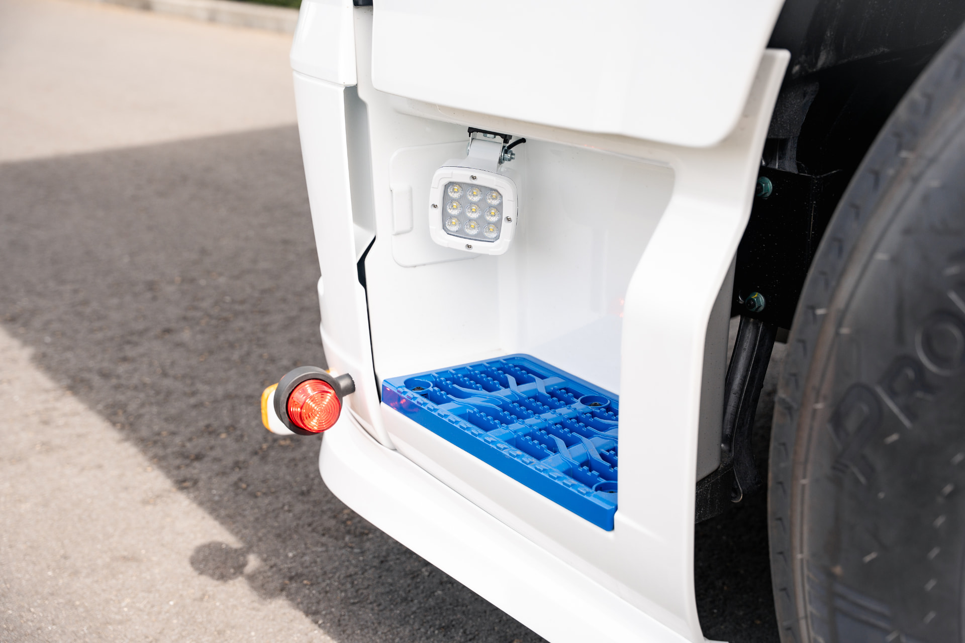 Detail van instap met werklamp en blauwe treeplaat op de truck