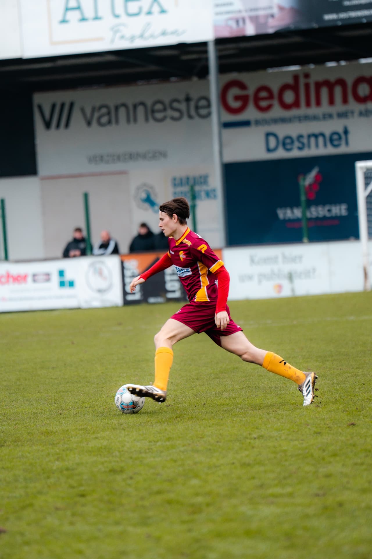 Speler sprint met de bal aan de voet langs de reclameborden