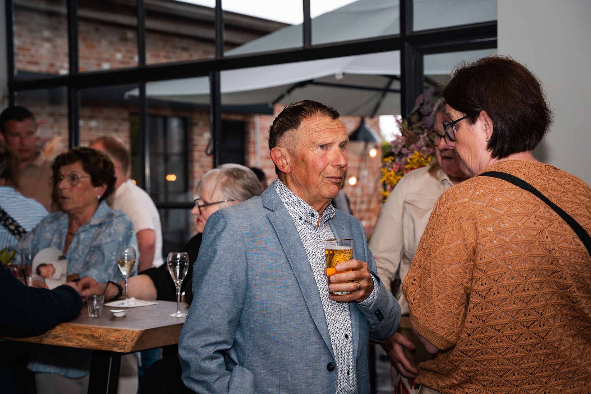 Gast met een glas bier in gesprek tijdens de babyborrel