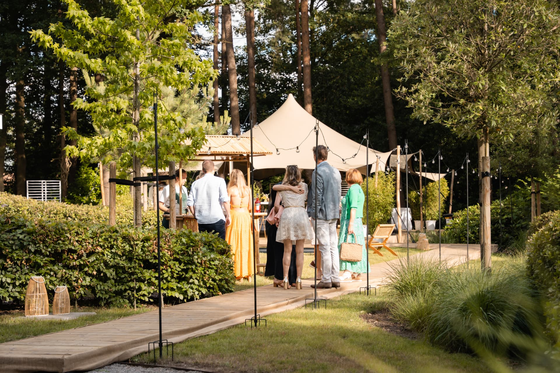 Gasten wandelen over een houten pad naar de stretchtent