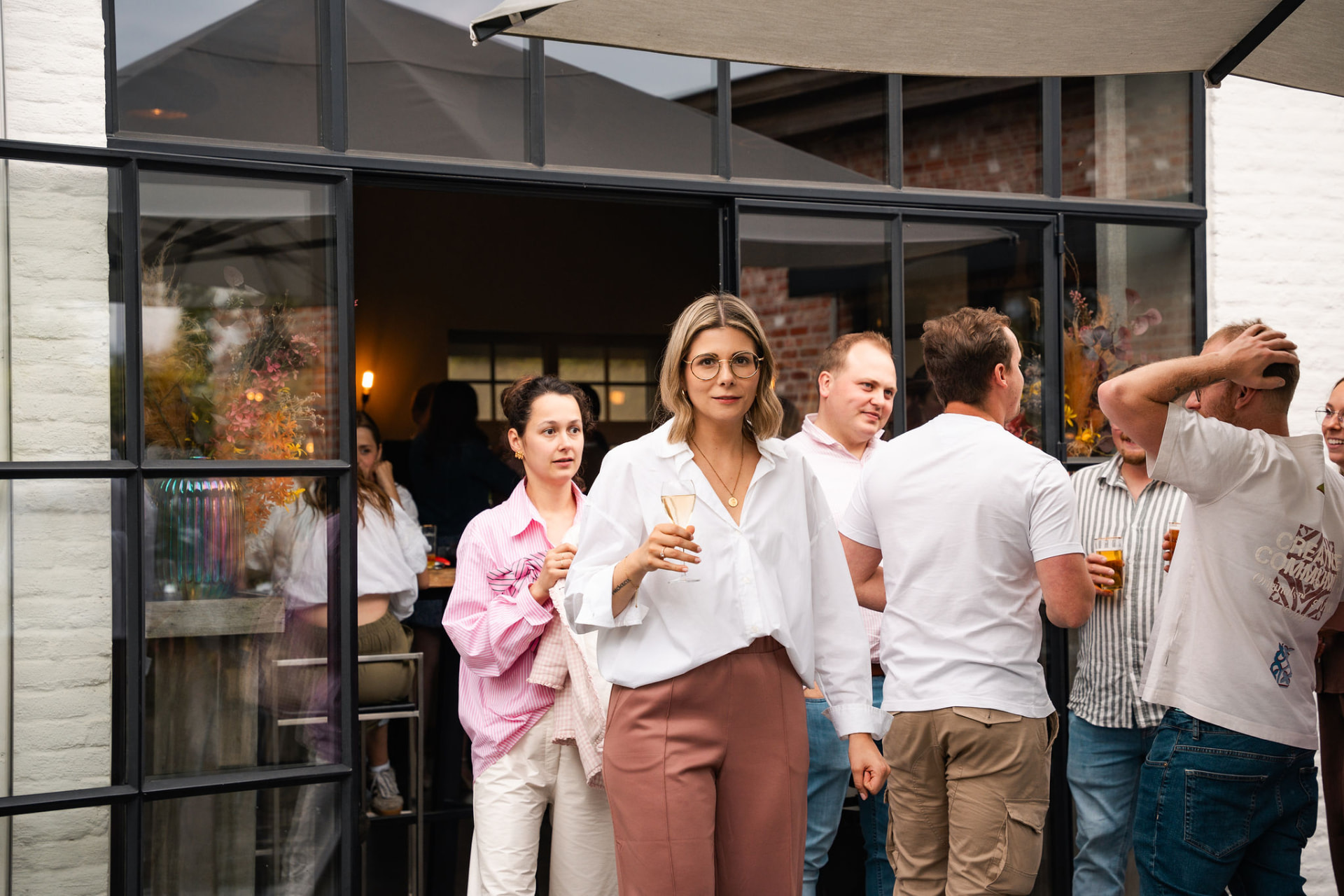 Gasten met een glas op het terras bij de glazen pui