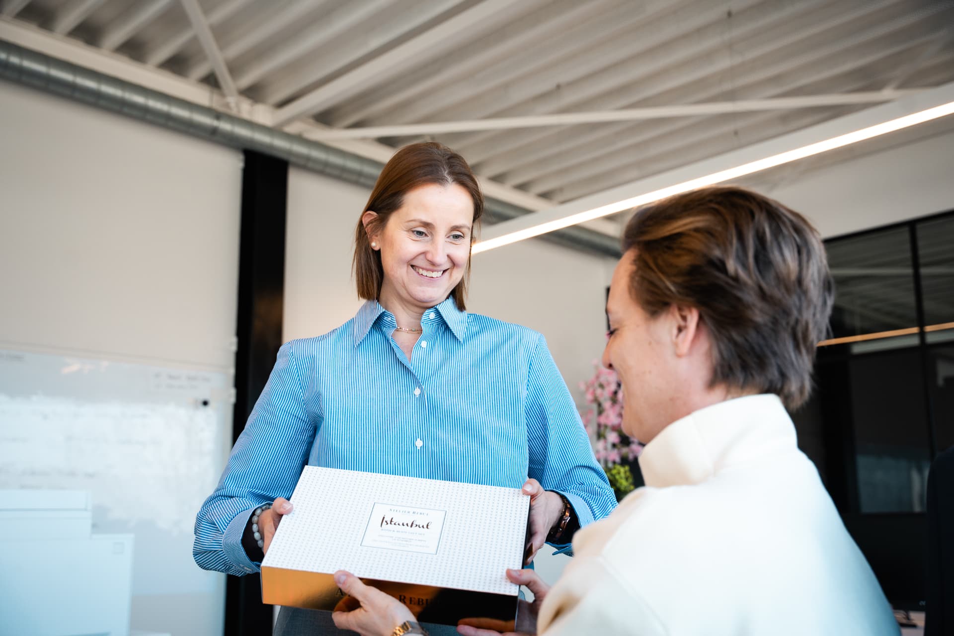 Collega's overhandigen elkaar een relatiegeschenk in het kantoor van Attent