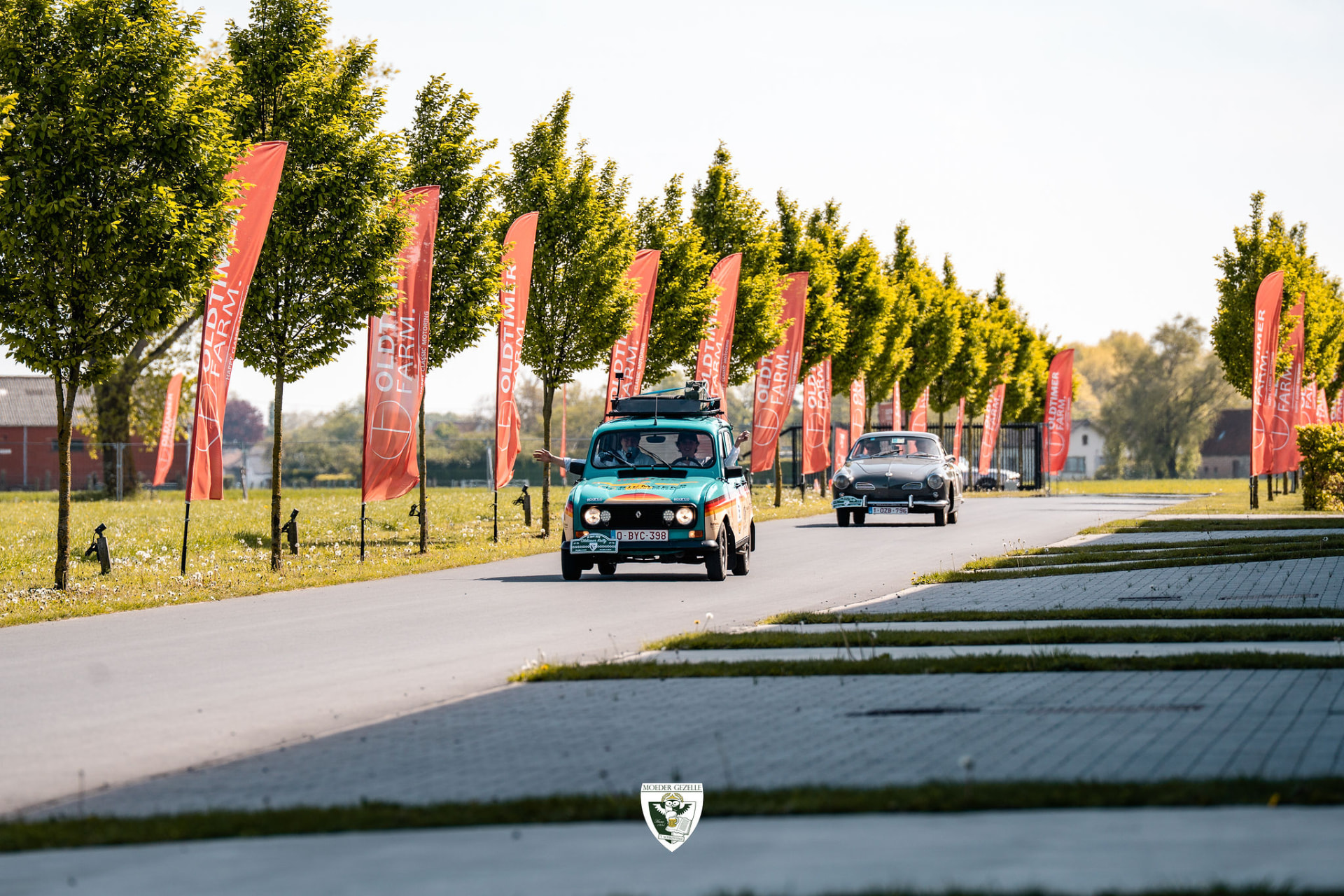 Turquoise Renault 4 en Karmann Ghia op de oprit langs de Oldtimer Farm-vlaggen