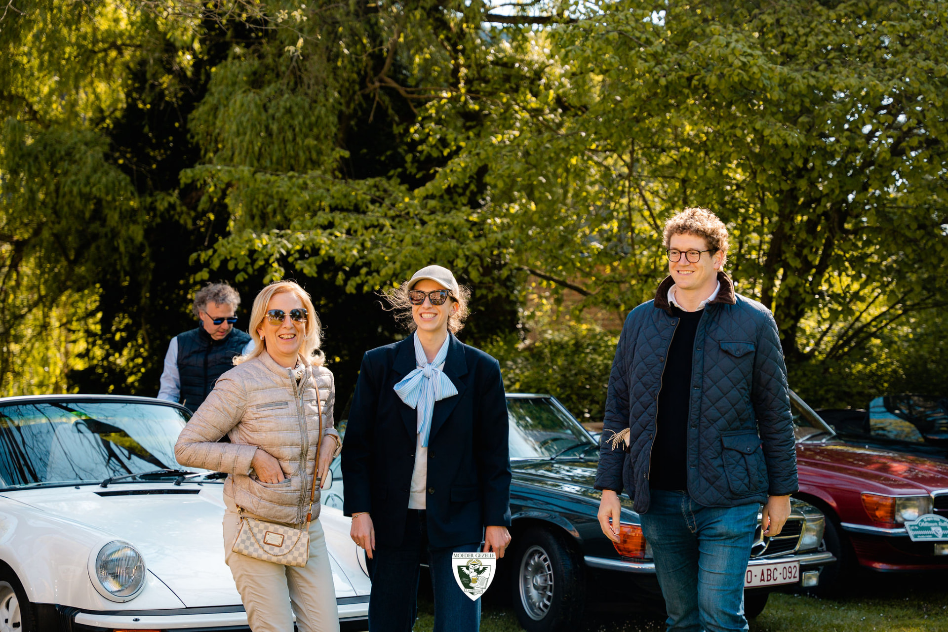 Lachende deelnemers voor een witte Porsche