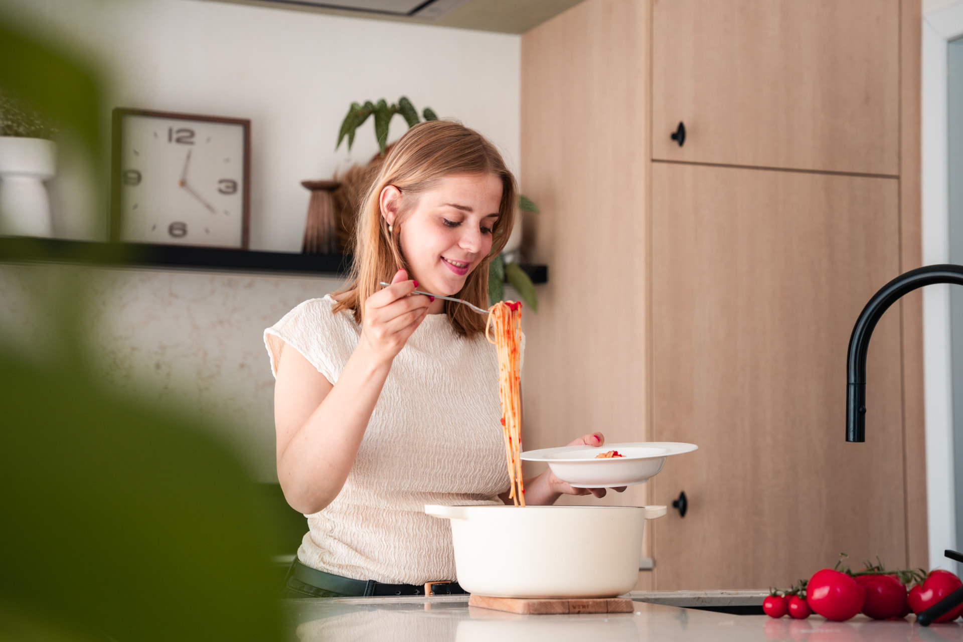 Vrouw die pasta uit een pot op een bord schept