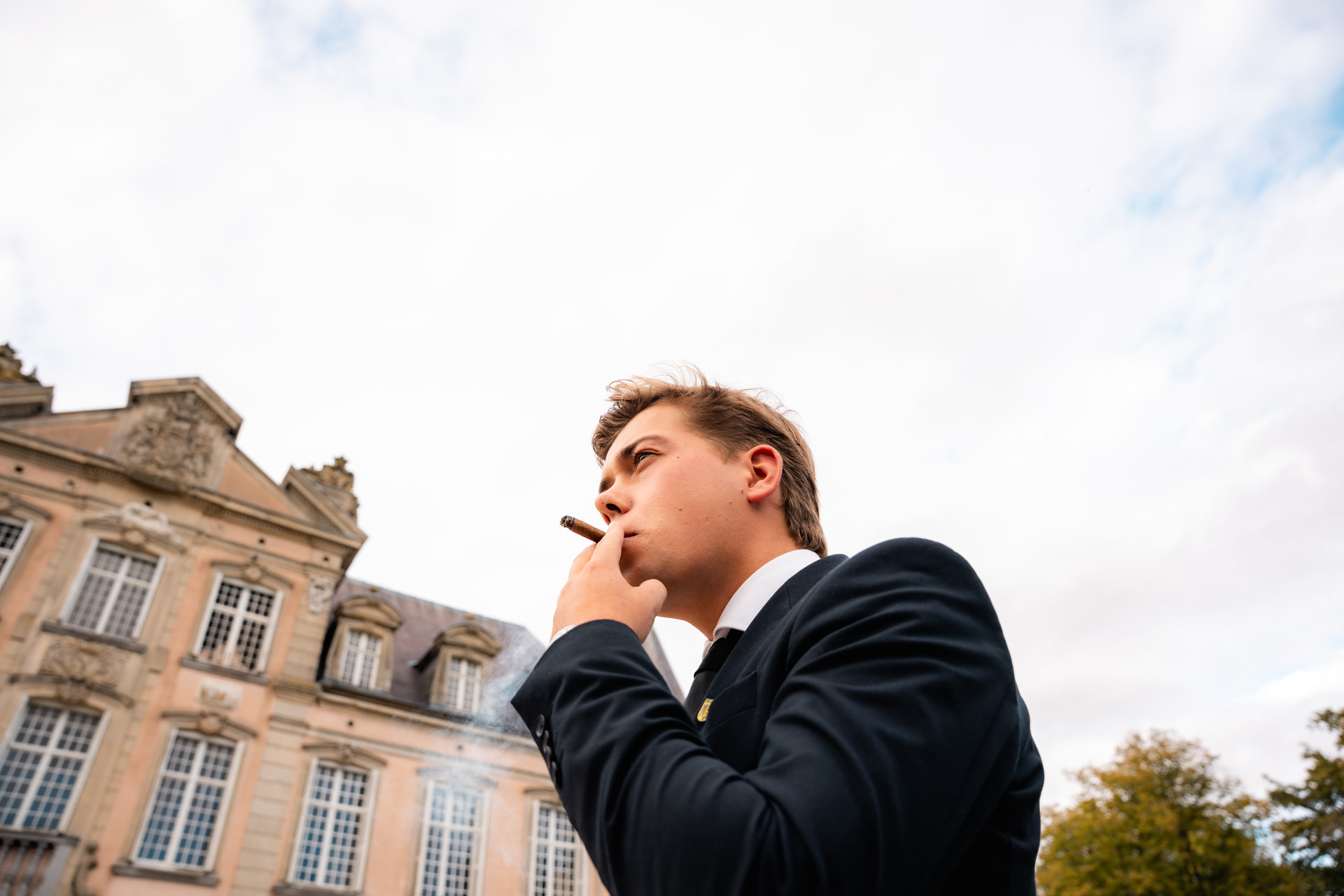 Clublid met sigaar voor de gevel van het kasteel