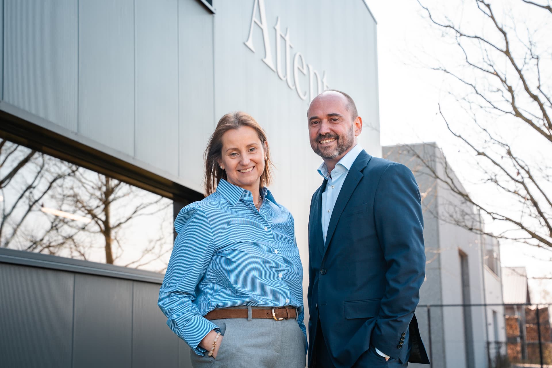 Twee zaakvoerders van Attent aan de gevel van het gebouw
