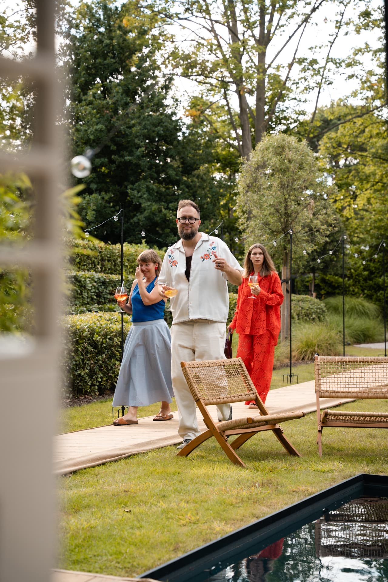 Gasten wandelen langs het zwembad met een glas in de hand