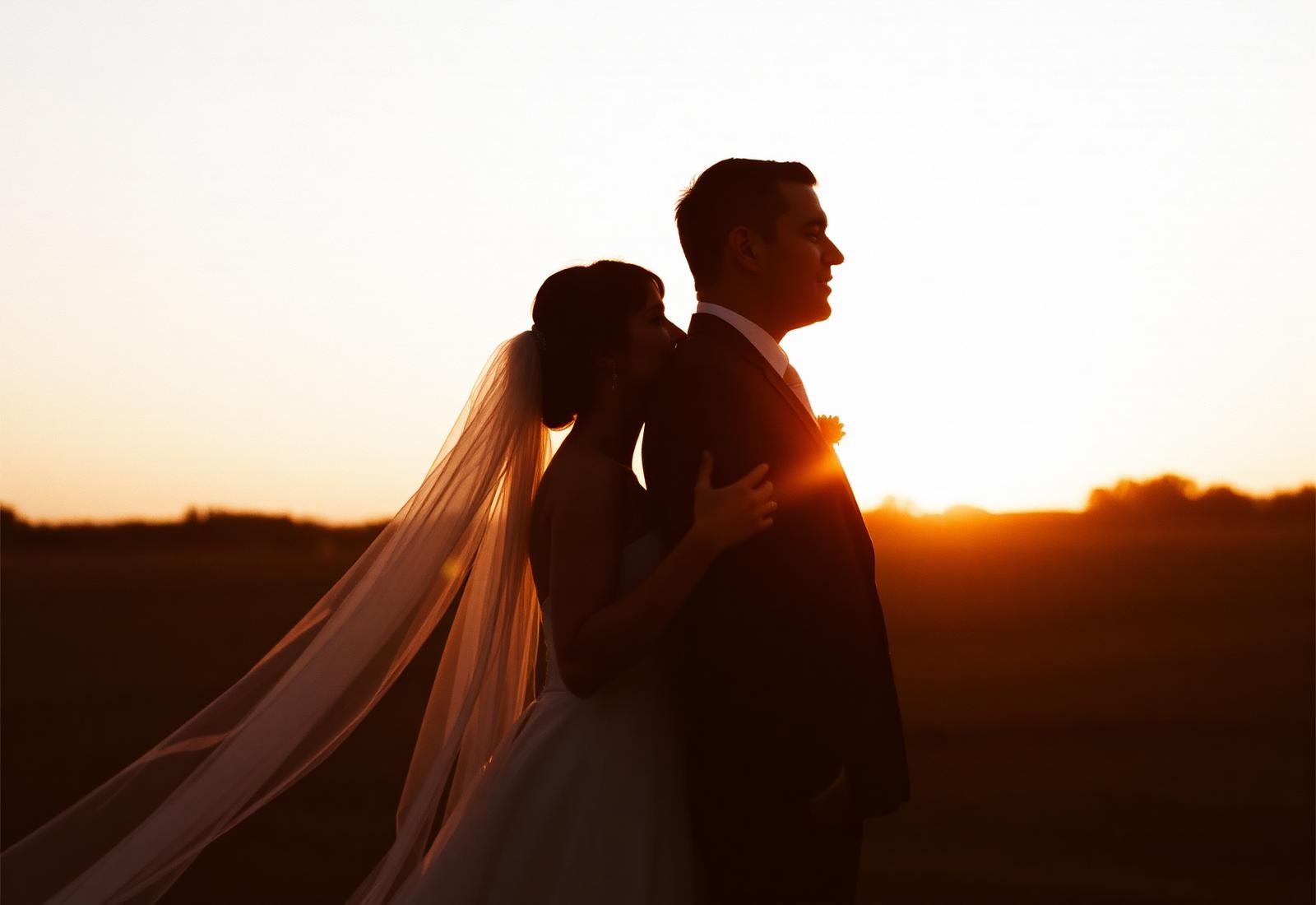 Bruidspaar in silhouet tegen de ondergaande zon